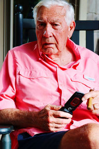 Young man using mobile phone while sitting on laptop