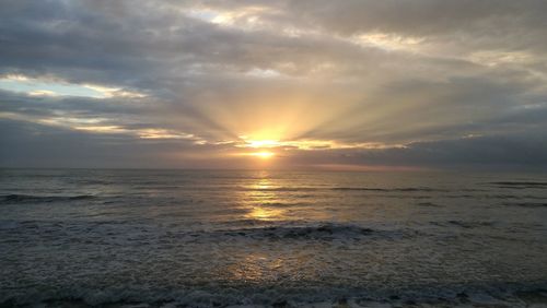 Scenic view of sea against dramatic sky during sunset