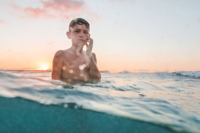 Portrait of man swimming in sea during sunset