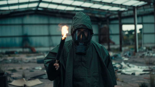 Soldier man with gas mask in a destroyed building by war with torch