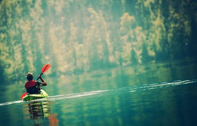 Rear view of man kayaking on lake