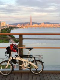 Bicycle parked by railing against buildings in city