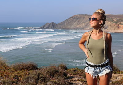 Young woman wearing sunglasses standing on beach