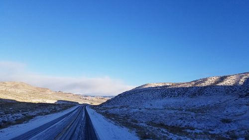 Road amidst mountains against clear blue sky