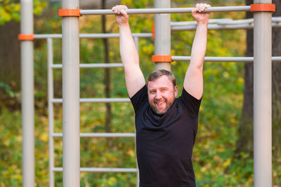 Man hanging on outdoor play equipment in park