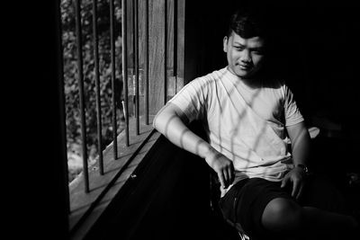 Young man looking through window at home