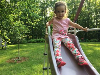 Portrait of girl sitting on slide in playground