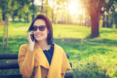 Portrait of smiling young woman using smart phone outdoors