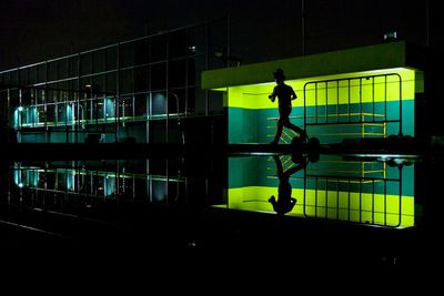 Full length of silhouette man standing by swimming pool