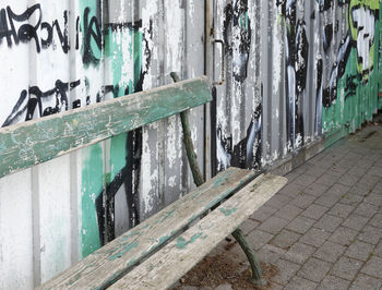 Empty old bench by graffiti wall