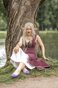 Young woman sitting on tree trunk