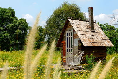 House amidst trees and plants on field against sky