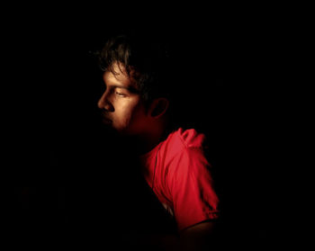 Portrait of young man against black background