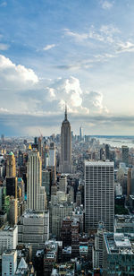 Aerial view of city buildings against cloudy sky