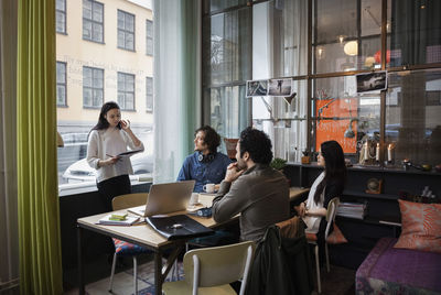 Creative businesswoman sharing ideas with team in modern office