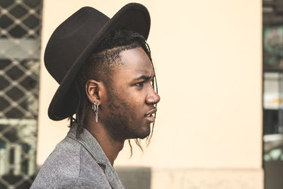 Side view of young man wearing hat looking away in city