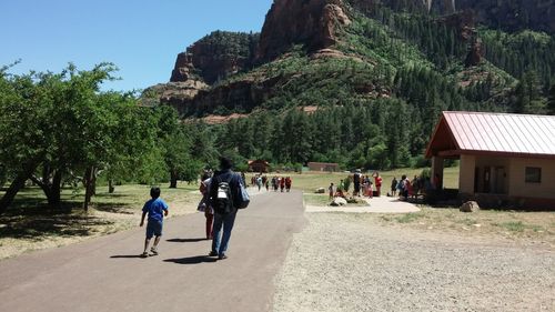 People walking on footpath against mountain