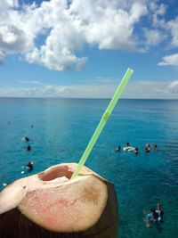 Close-up of hand holding ice cream over sea against sky