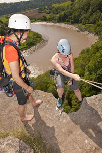 Friend supervising her friend as she descendes steep cliff in wales