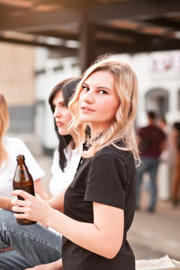 Young woman holding ice cream standing against bottle