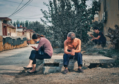 Men sitting on bridge against trees