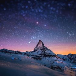 Scenic view of snowcapped mountains against sky at night