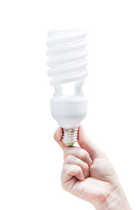 Close-up of hand holding light bulb against white background