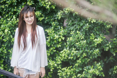 Young woman standing against plants