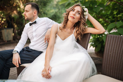 Bride and bridegroom sitting on chairs at park