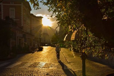 People walking on street in city at sunset