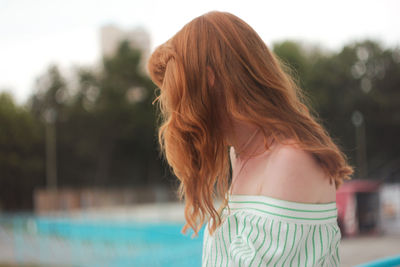 Rear view of woman standing at swimming pool