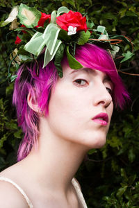 Close-up of young woman with flowers and pink hair
