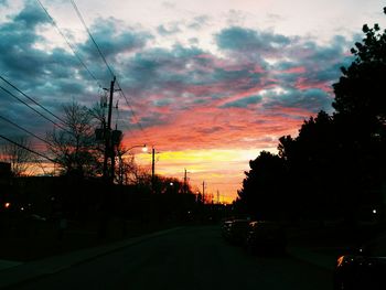 Cars on road against cloudy sky at sunset