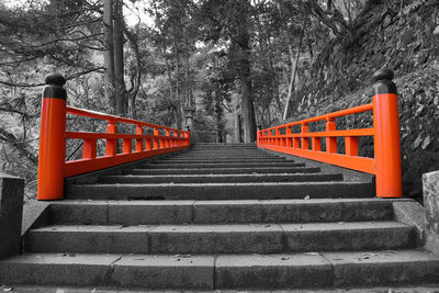 Red railing by trees against sky