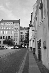 Empty road amidst buildings in city