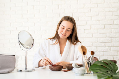 Young woman holding food on table against wall