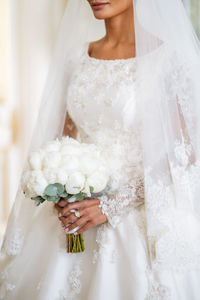 Midsection of bride holding bouquet