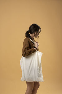 Young woman standing against yellow background