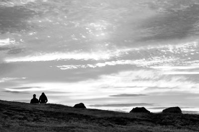 Silhouette people on field against sky