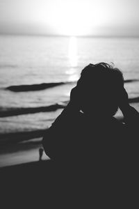 Rear view of silhouette woman on beach against sky