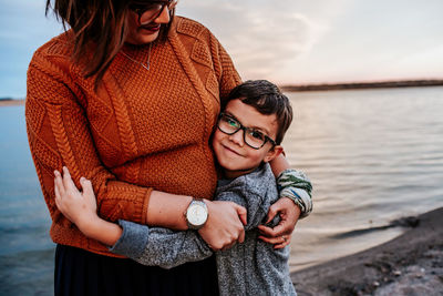 Mom hugging young son on the shore of a lake on a autumn evening