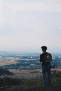 Rear view of man photographing on landscape against sky