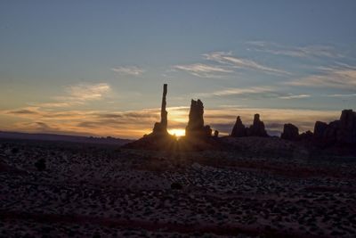 Silhouette people on desert against sky during sunset