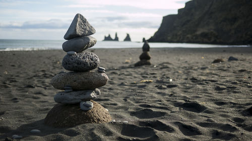 Stack of pebbles on beach against sky