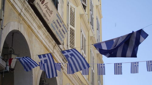 Low angle view of greek flags against window