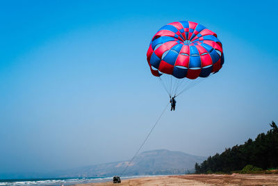 People parasailing over sea against clear blue sky