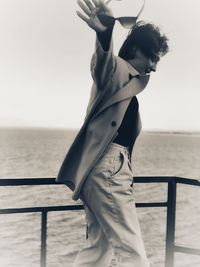 Woman standing by railing against sea