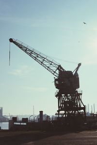 Cranes against sky at sunset