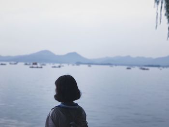 Rear view of woman in lake against sky