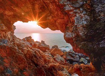 Rock formation on sea against sky during sunset